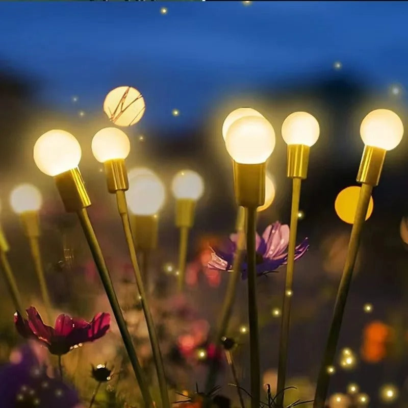 Lampes solaires lucioles LED parmi des fleurs violettes en soirée